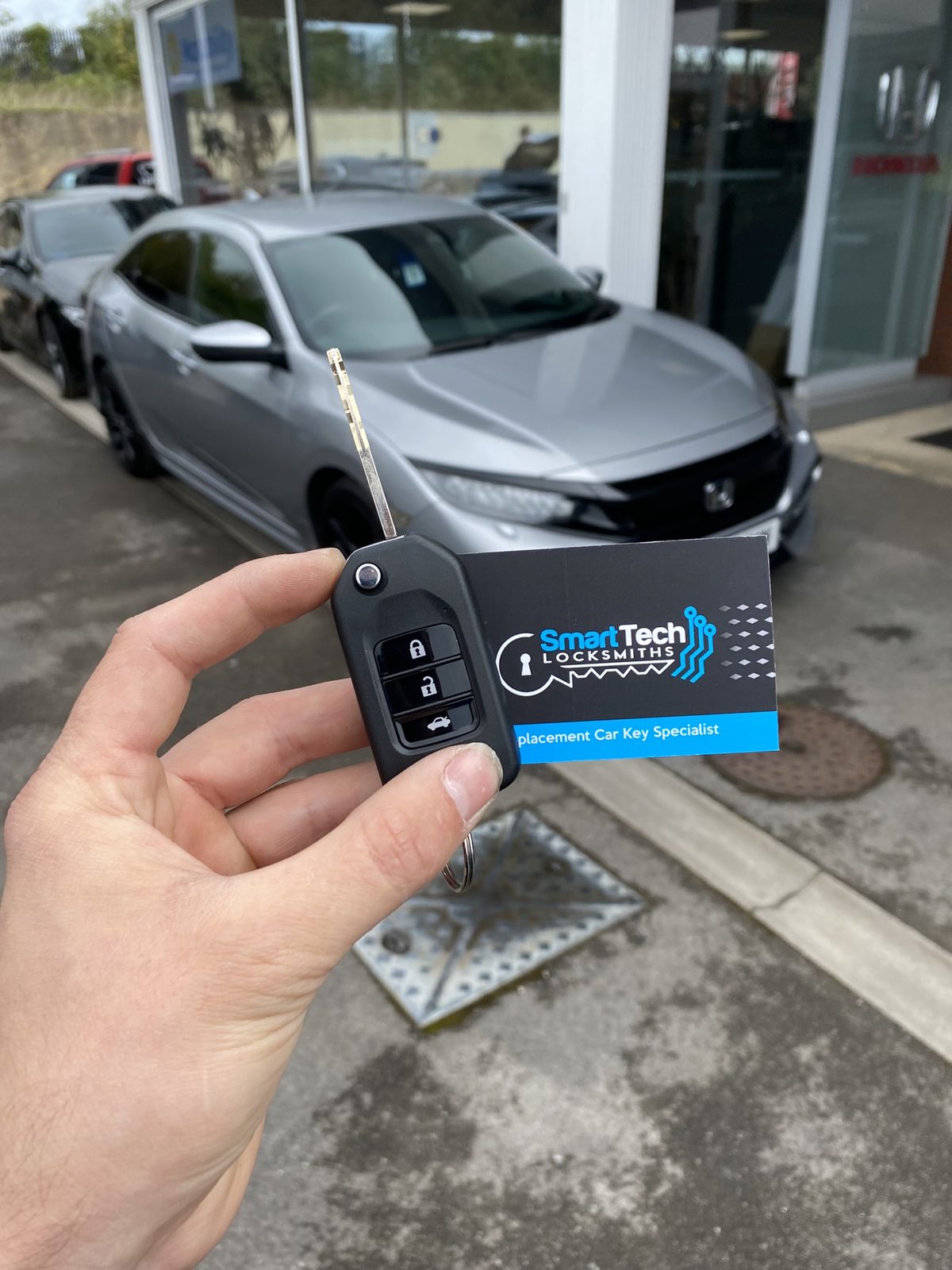 Honda Civic flip key cut and coded in Hampshire by SmartTech Auto Locksmiths, key and business card held in front of the vehicle