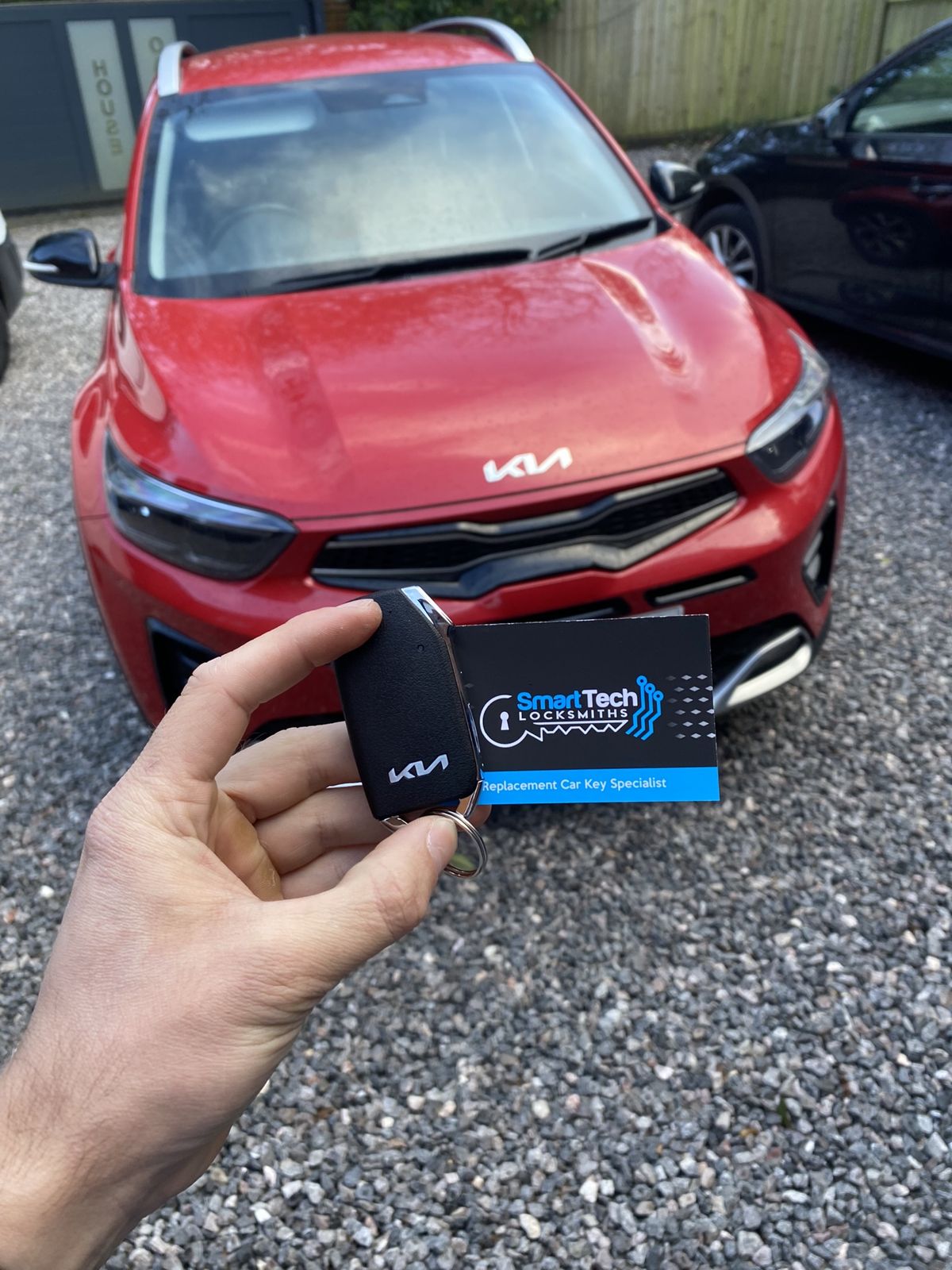 Kia Stonic replacement key in Salisbury by SmartTech Auto Locksmiths, key and business card held in front of the vehicle
