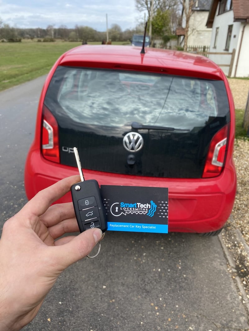 Volkswagen up! flip key cut and coded in Hampshire by SmartTech Auto Locksmiths, key and business card held in front of the vehicle