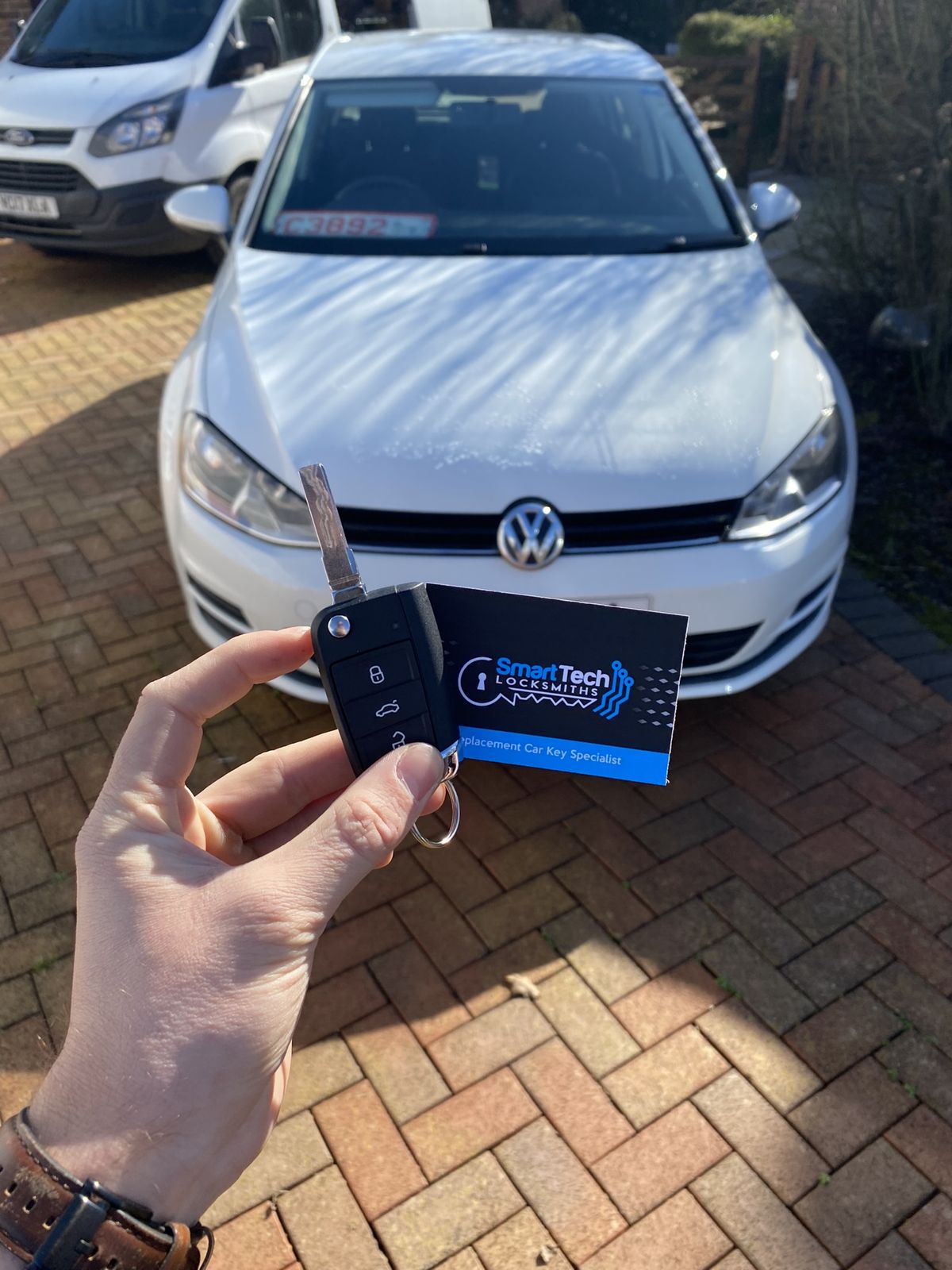 Volkswagen Golf spare flip key in New Milton by SmartTech Auto Locksmiths, key and business card held in front of the vehicle