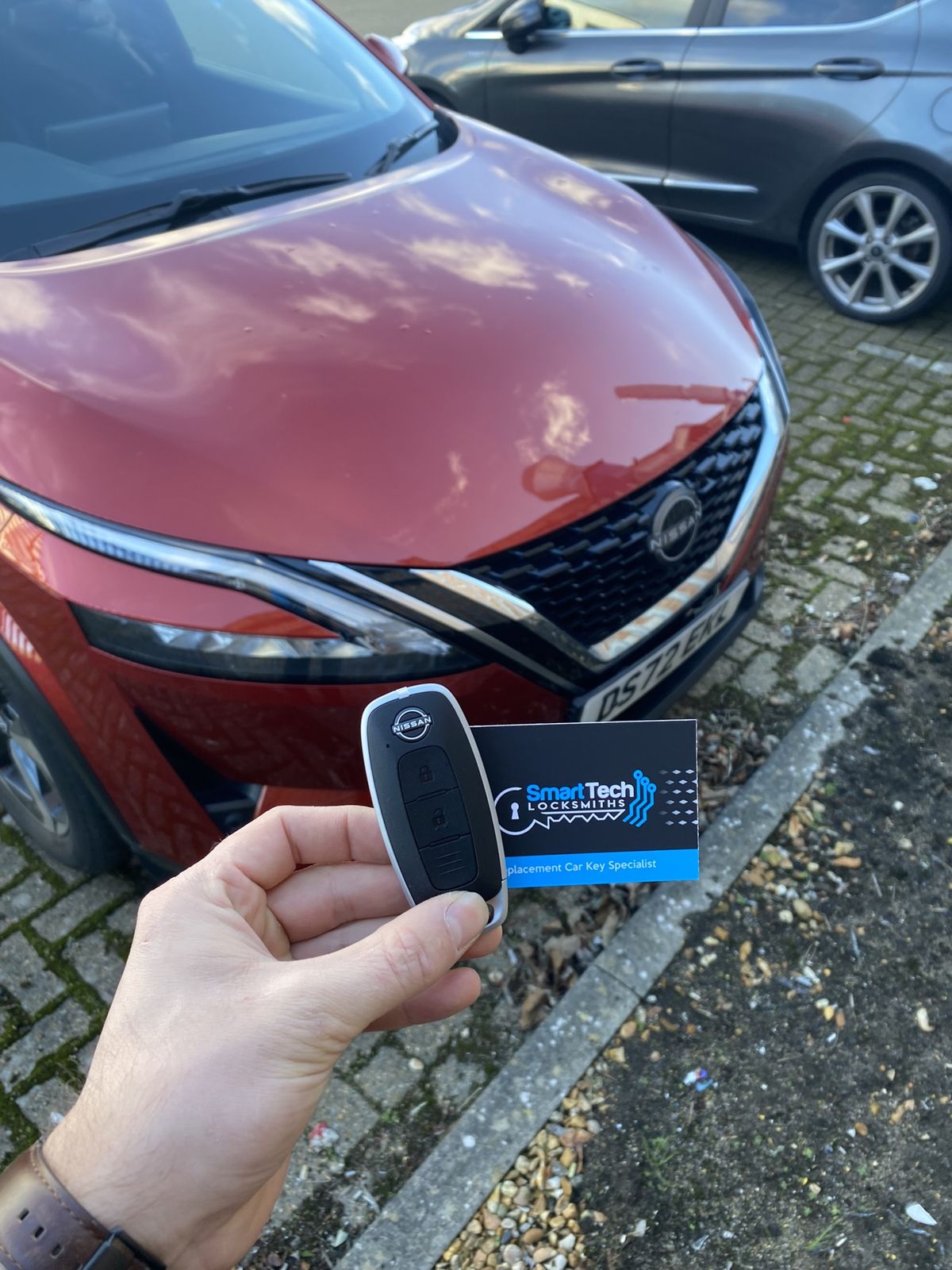 Nissan Qashqai smart key programmed in Bishop's Waltham by SmartTech Auto Locksmiths, key and business card held in front of the vehicle