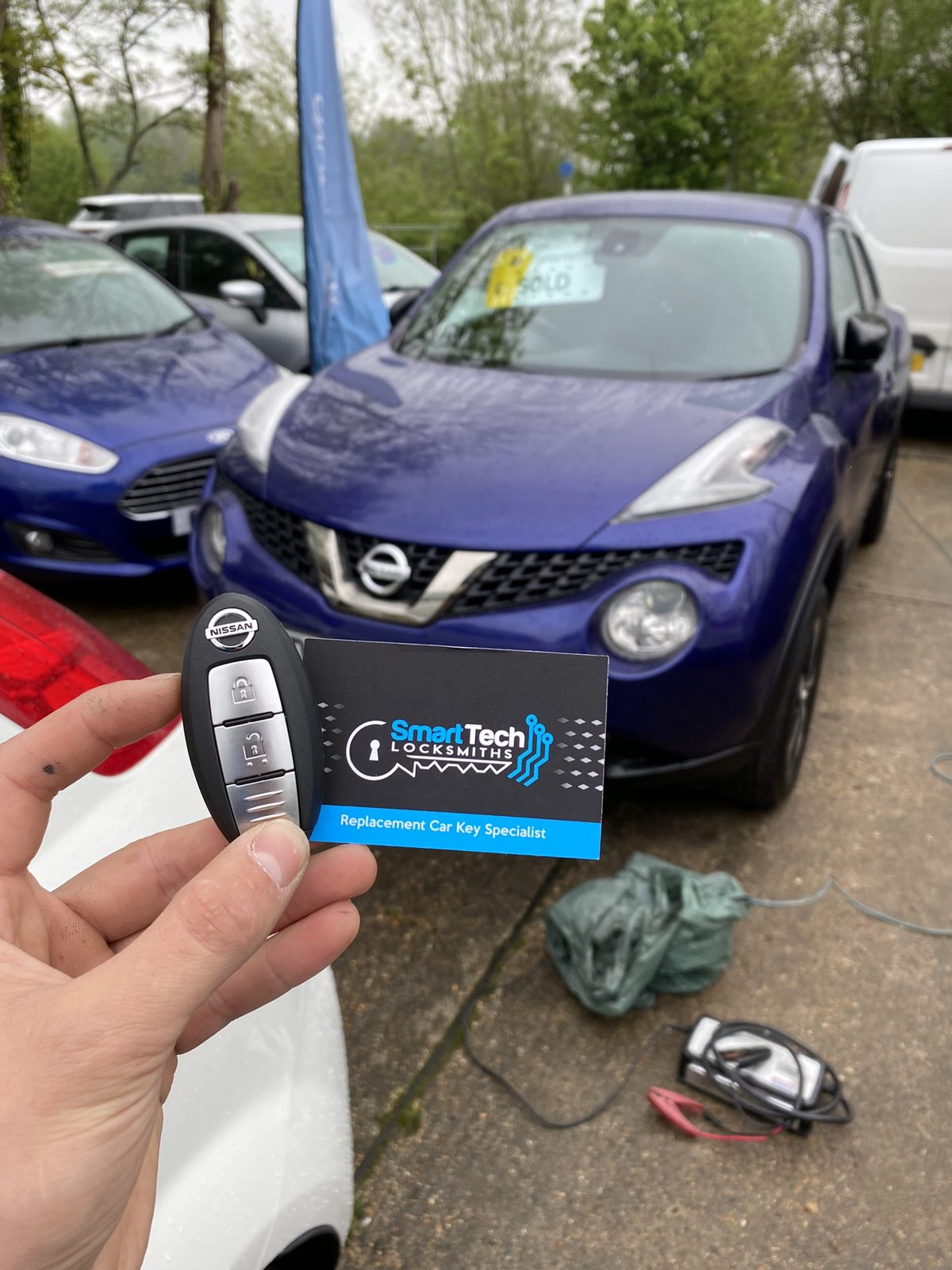 Nissan Juke smart key programmed in Hampshire by SmartTech Auto Locksmiths, key and business card held in front of the vehicle