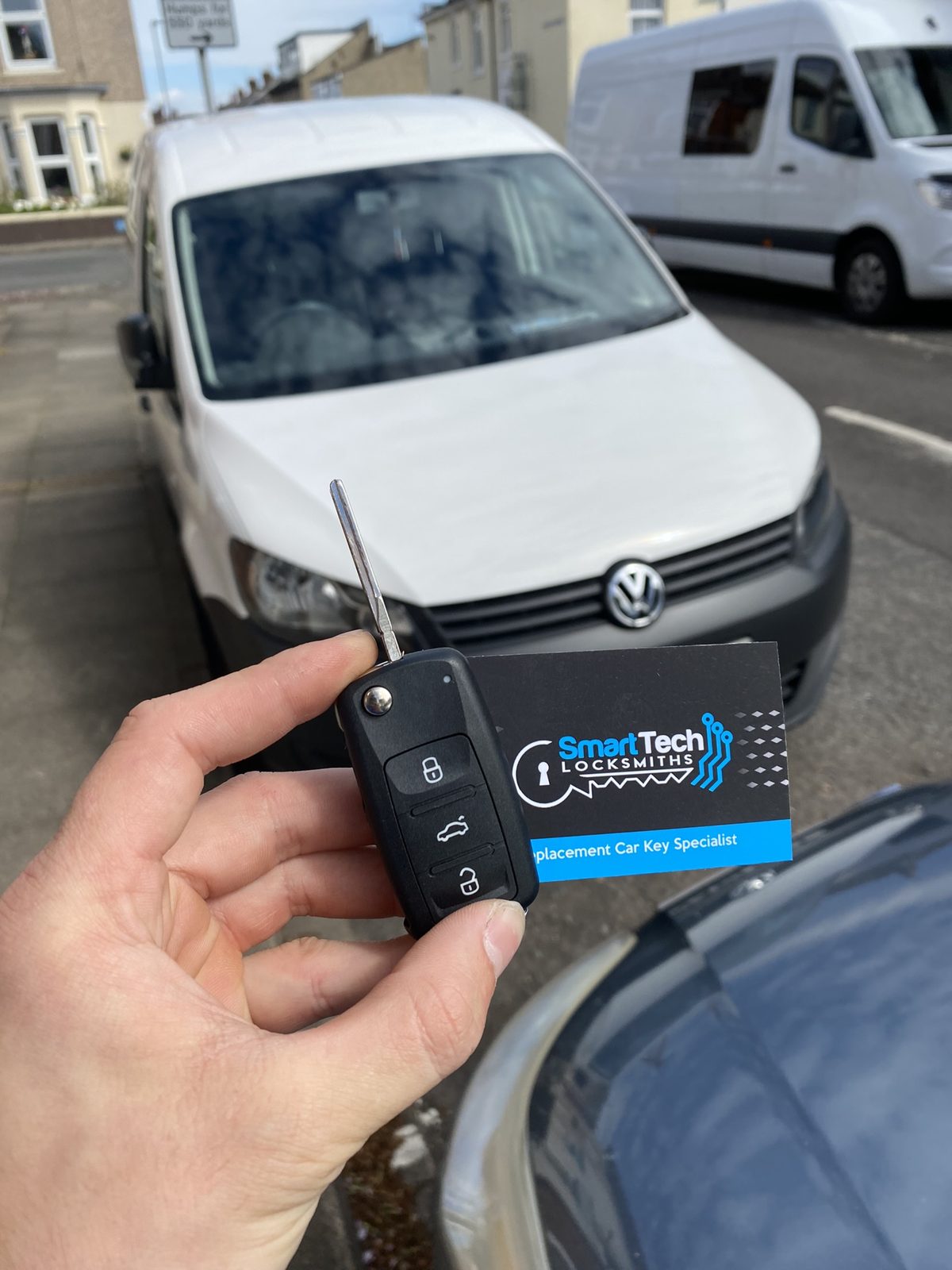 Volkswagen Caddy flip key cut and coded in Hampshire by SmartTech Auto Locksmiths, key and business card held in front of the vehicle