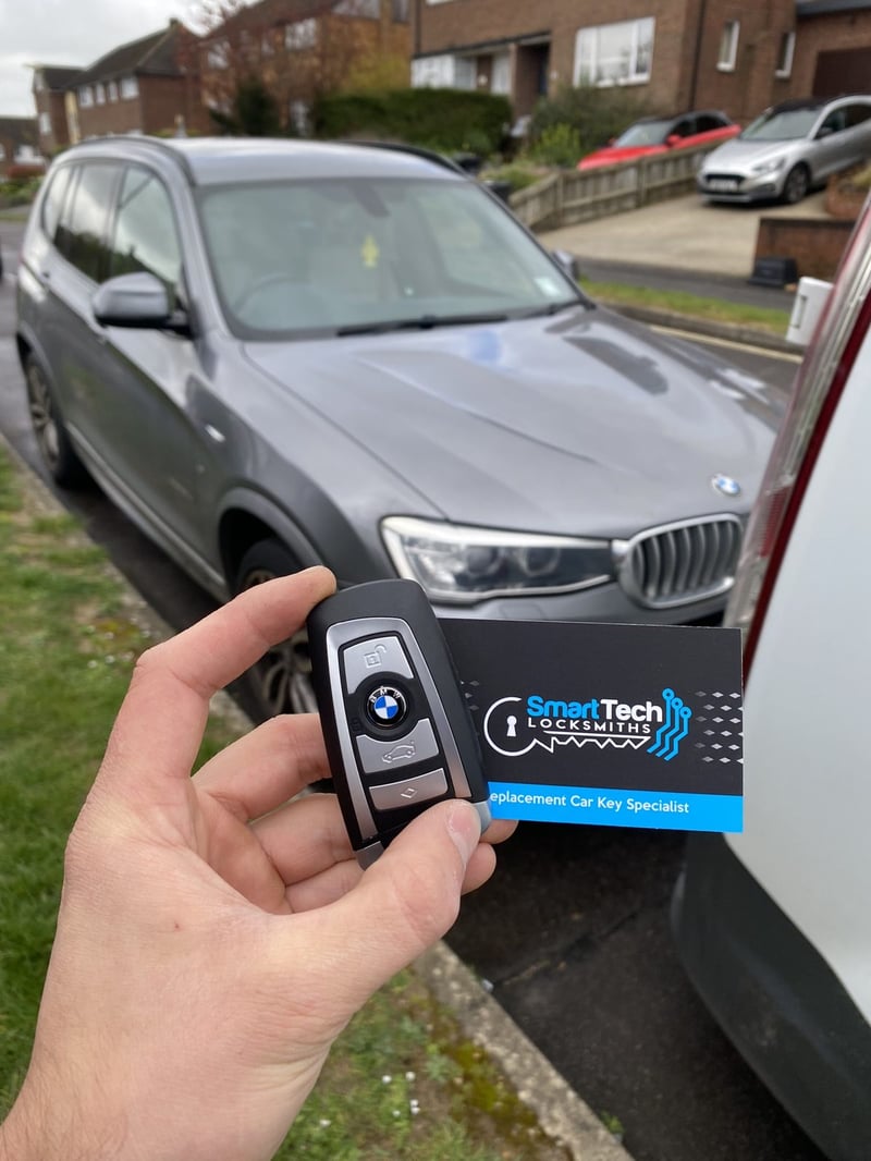 BMW X3 spare smart key in Hampshire by SmartTech Auto Locksmiths, key and business card held in front of the vehicle