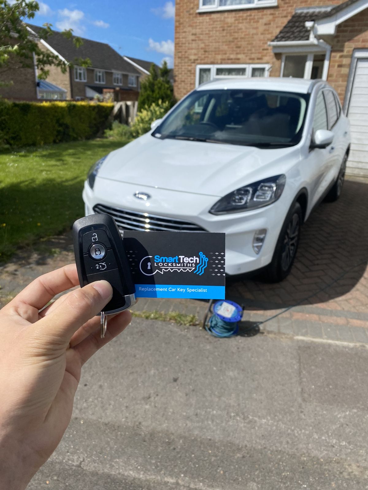 Ford Puma smart key programmed in Totton by SmartTech Auto Locksmiths, key and business card held in front of the vehicle