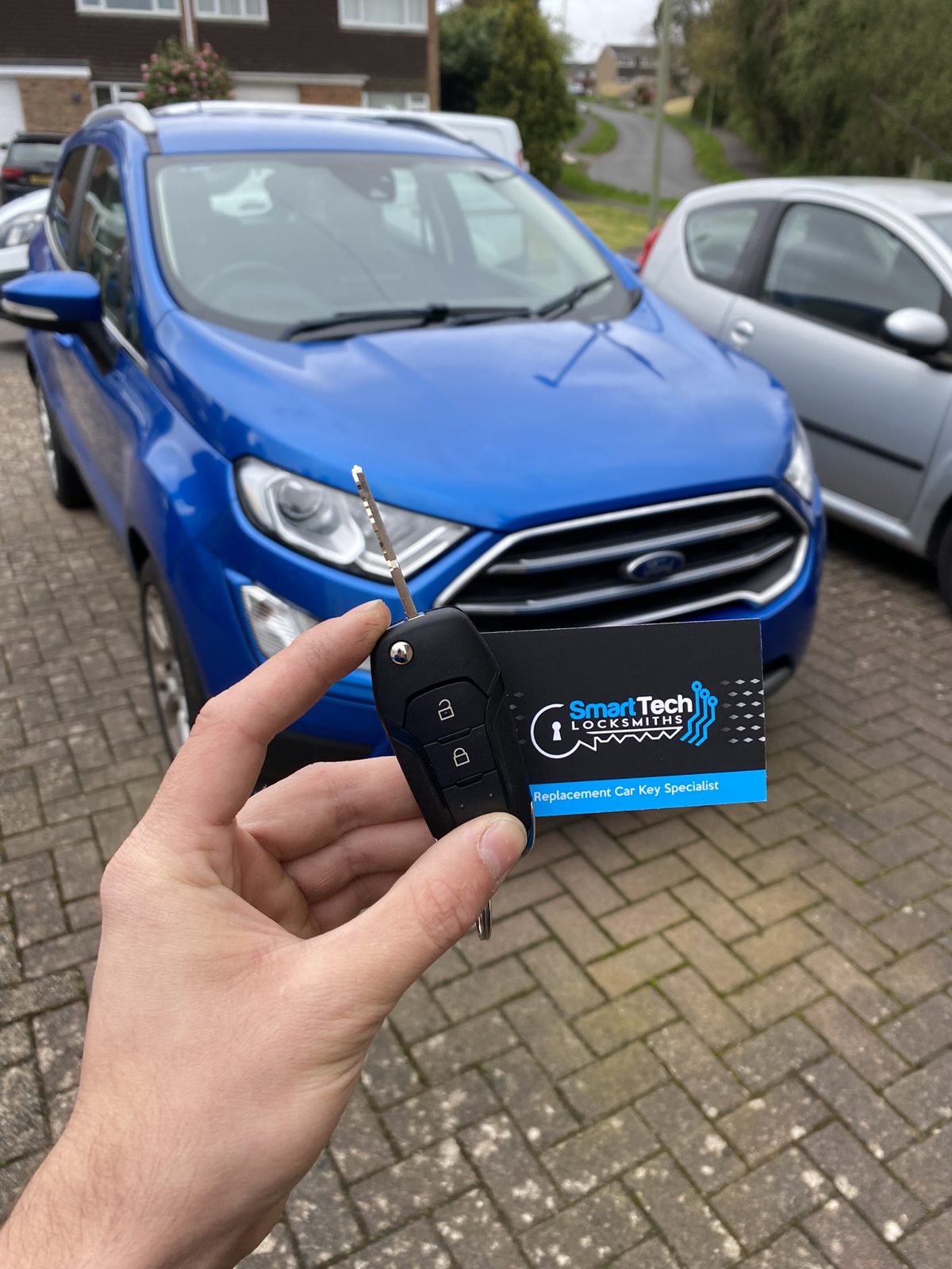 Ford EcoSport flip key cut and coded in Hampshire by SmartTech Auto Locksmiths, key and business card held in front of the vehicle