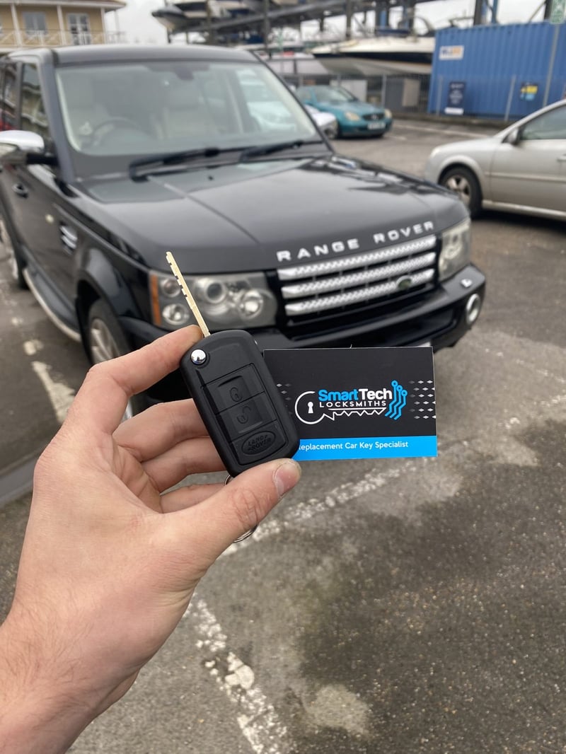Range Rover Sport flip key cut and coded in Hampshire by SmartTech Auto Locksmiths, key and business card held in front of the vehicle