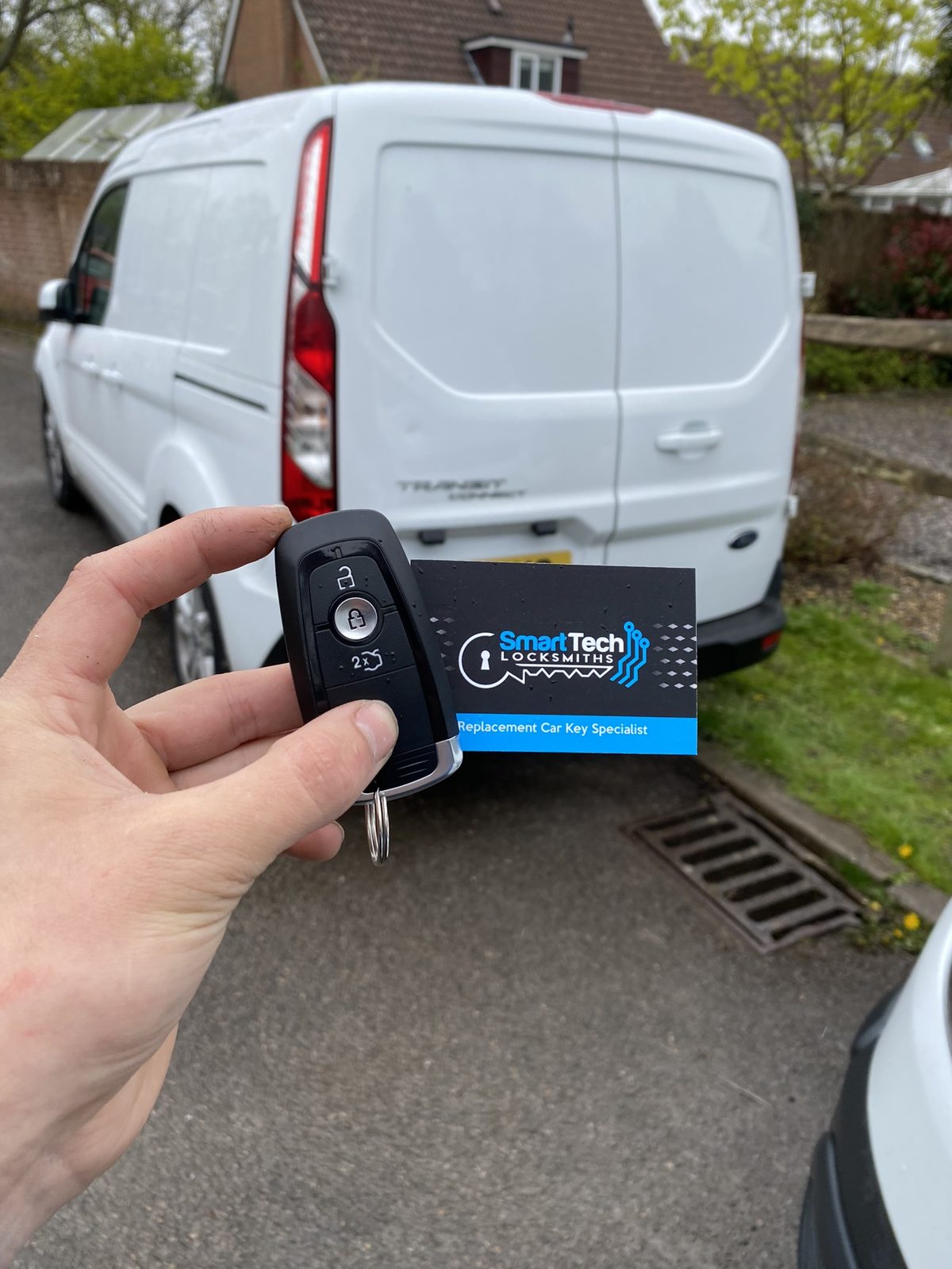 Ford Transit Custom van smart key programmed in Hampshire by SmartTech Auto Locksmiths, key and business card held in front of the vehicle