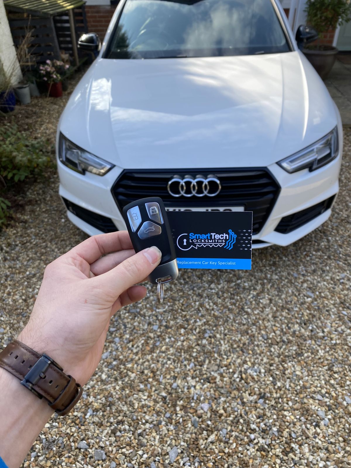 Audi A4 spare remote key in New Milton by SmartTech Auto Locksmiths, key and business card held in front of the vehicle