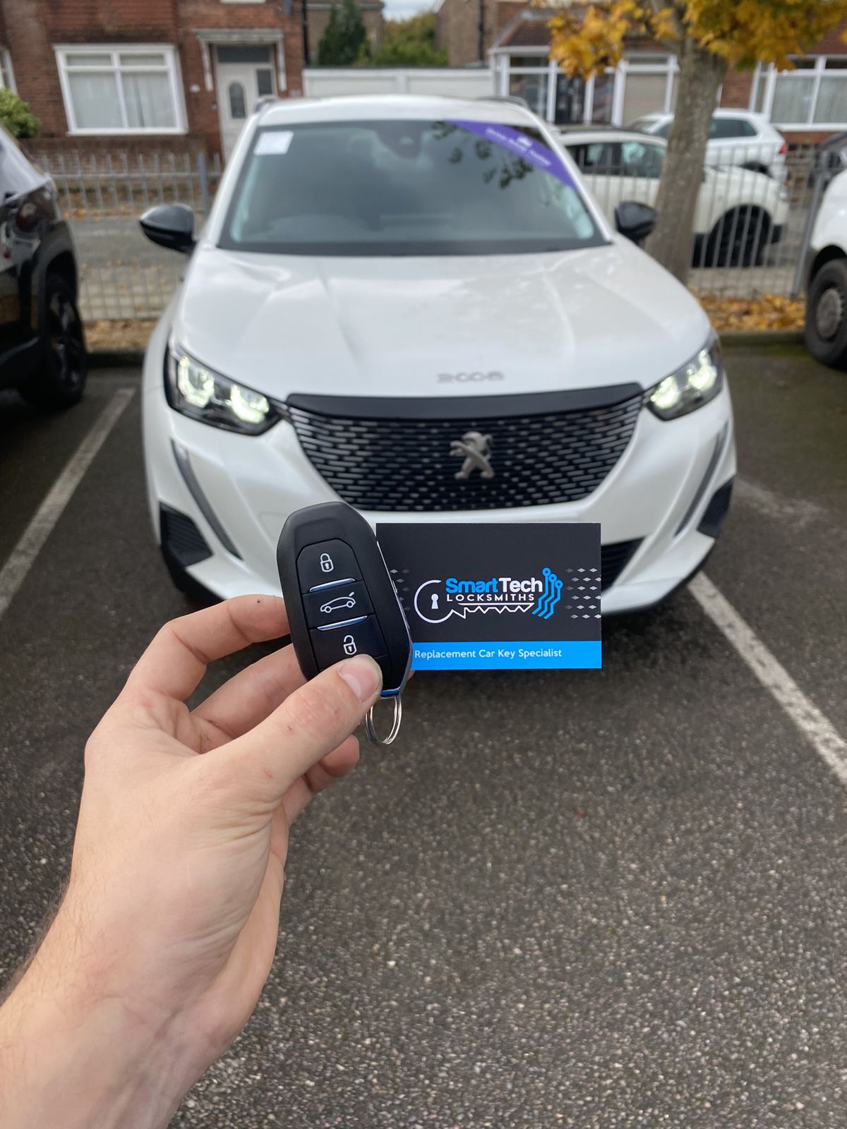 Peugeot 2008 smart key programmed in Winchester by SmartTech Auto Locksmiths, key and business card held in front of the vehicle