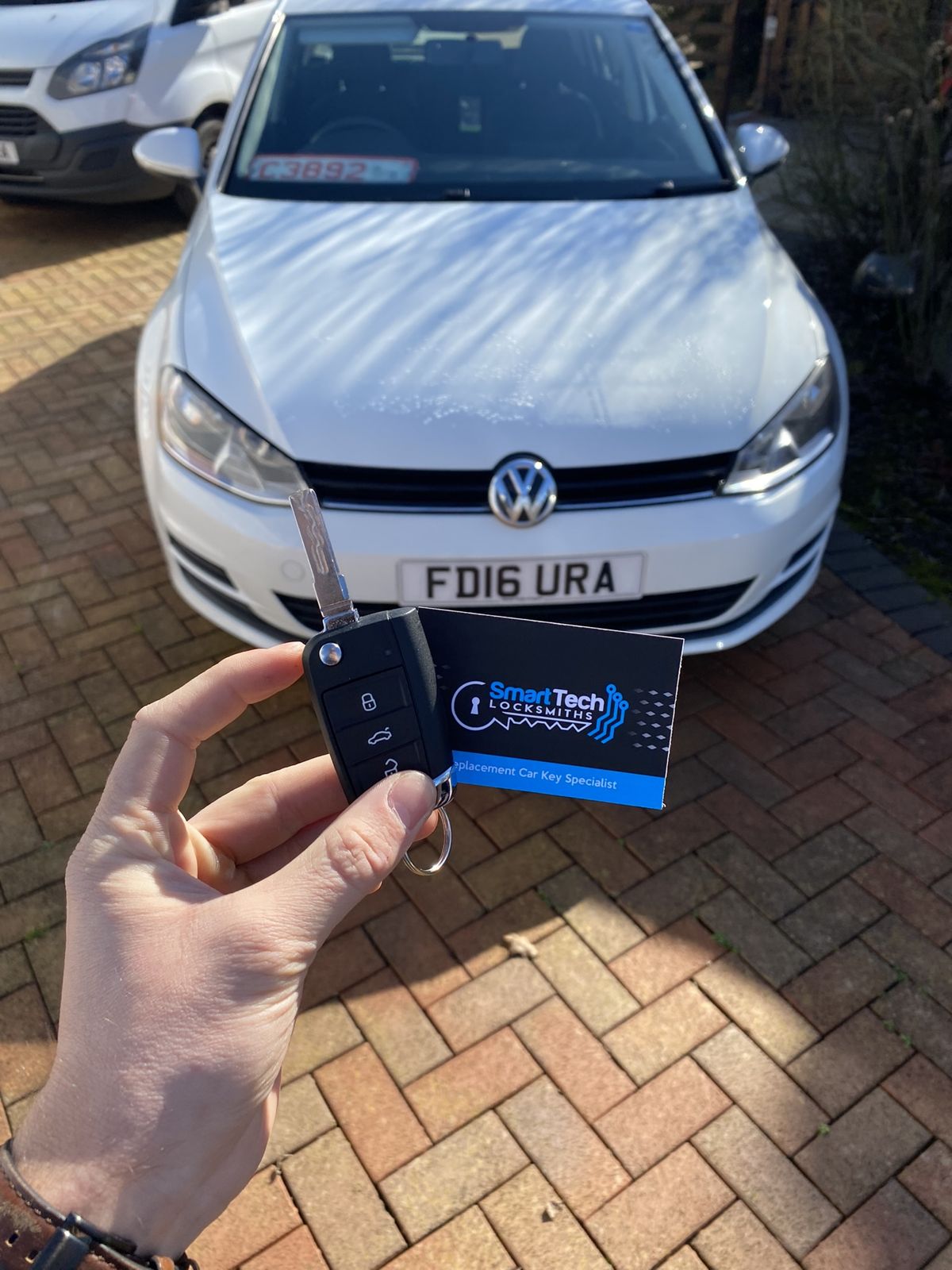 Volkswagen Polo flip key coded in New Forest by SmartTech Auto Locksmiths, key and business card held in front of the vehicle