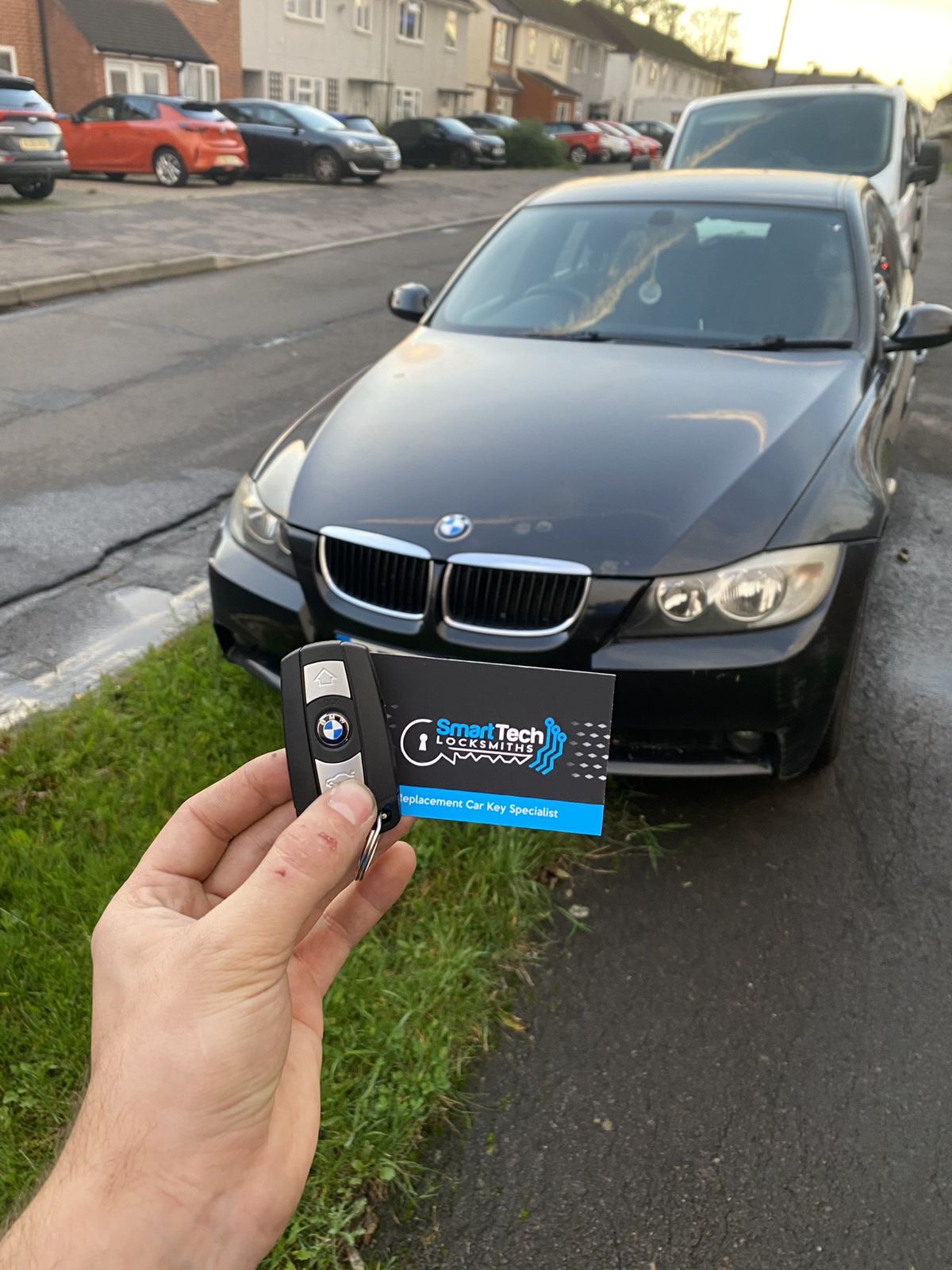 BMW 3 Series replacement key coded in Winchester by SmartTech Auto Locksmiths, key and business card held in front of the vehicle