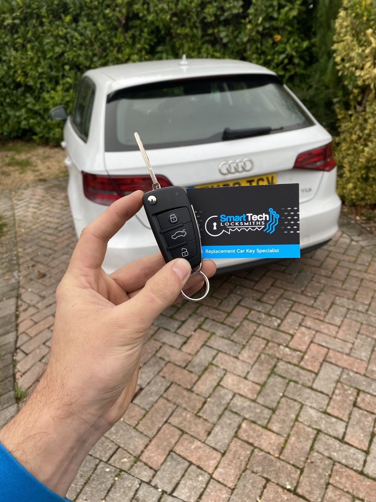 Audi A3 flip key cut and coded in New Forest by SmartTech Auto Locksmiths, key and business card held in front of the vehicle