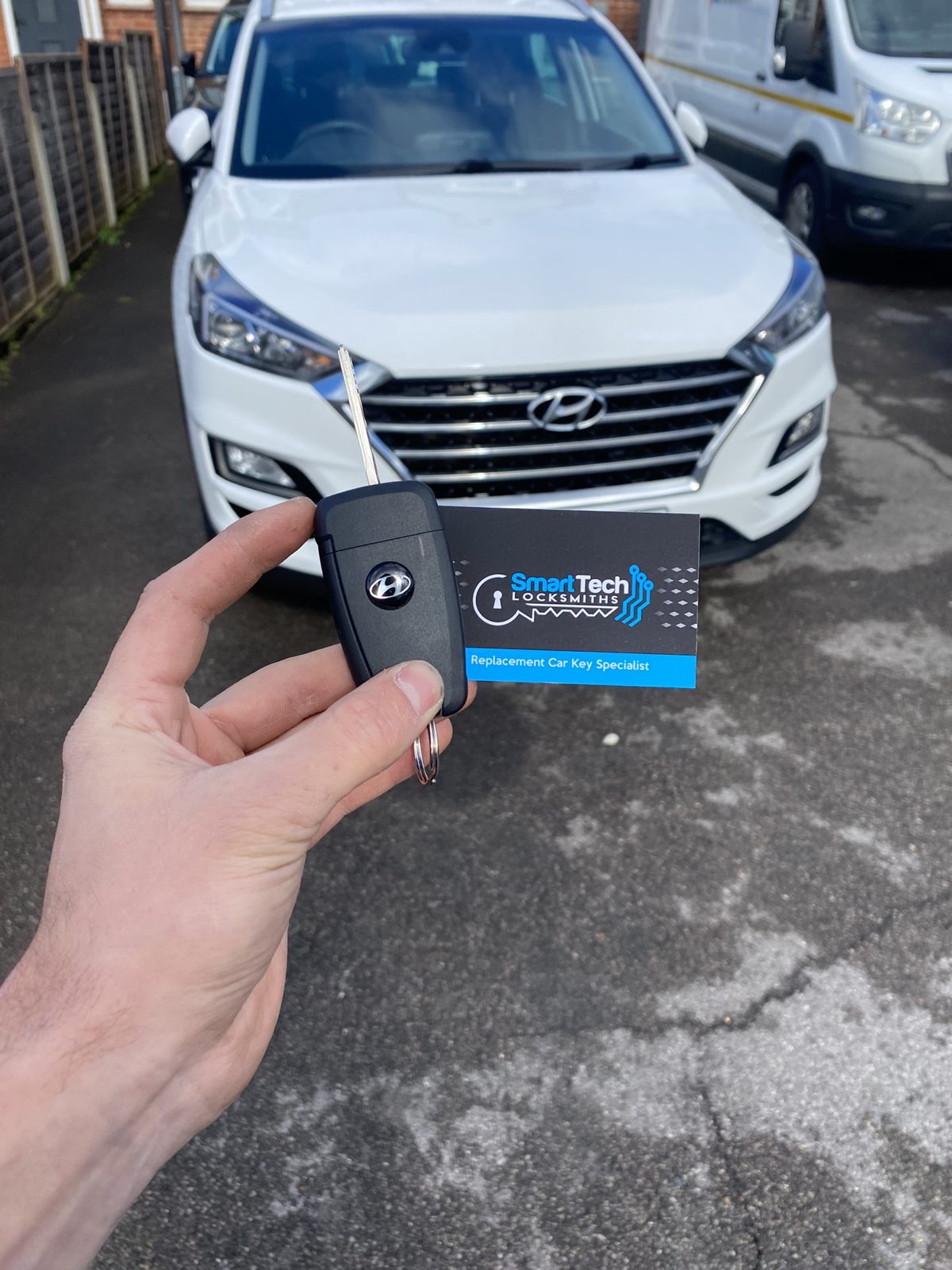 Hyundai Tucson spare smart key in Hampshire by SmartTech Auto Locksmiths, key and business card held in front of the vehicle