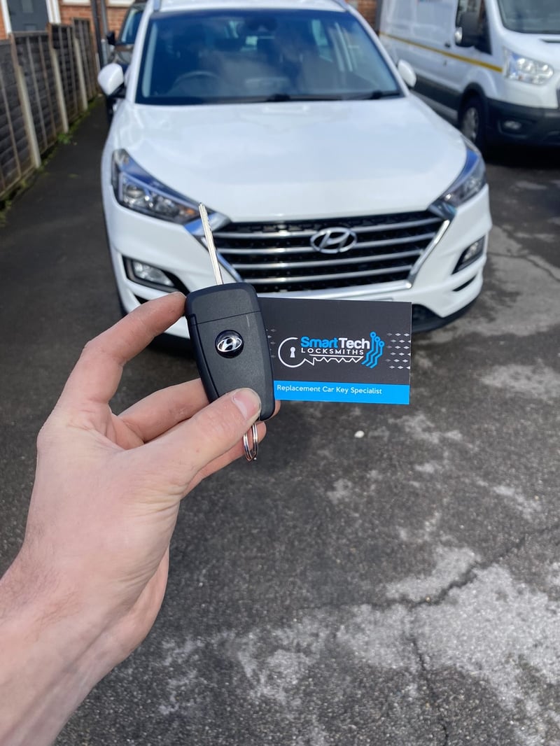Hyundai Tucson spare smart key in Hampshire by SmartTech Auto Locksmiths, key and business card held in front of the vehicle