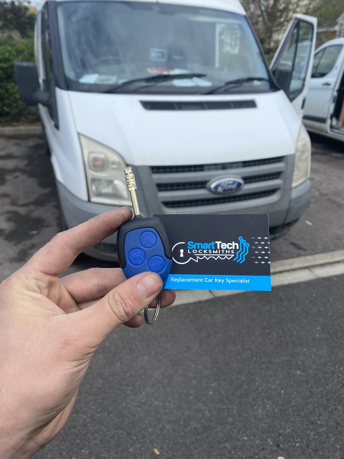 Ford Transit van remote key in Hampshire by SmartTech Auto Locksmiths, key and business card held in front of the vehicle