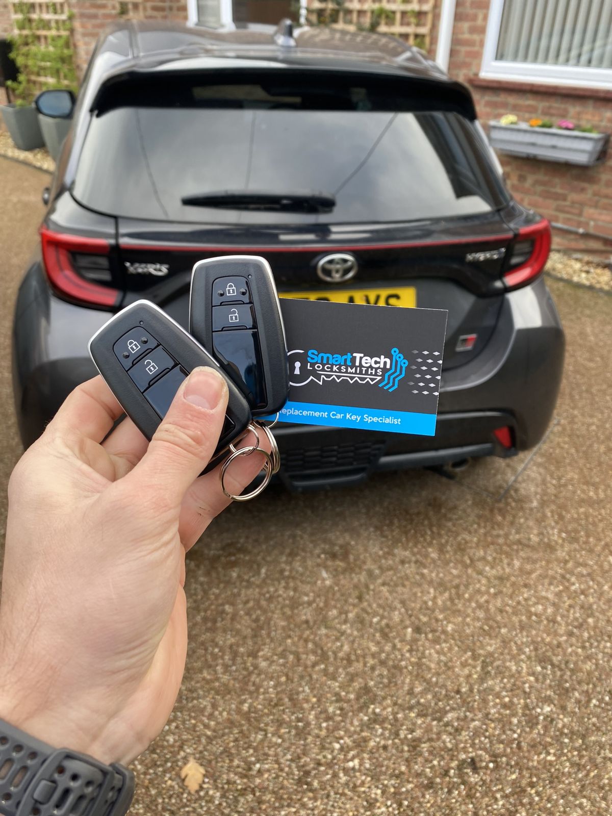 Toyota Yaris smart key programmed in Bitterne by SmartTech Auto Locksmiths, key and business card held in front of the vehicle