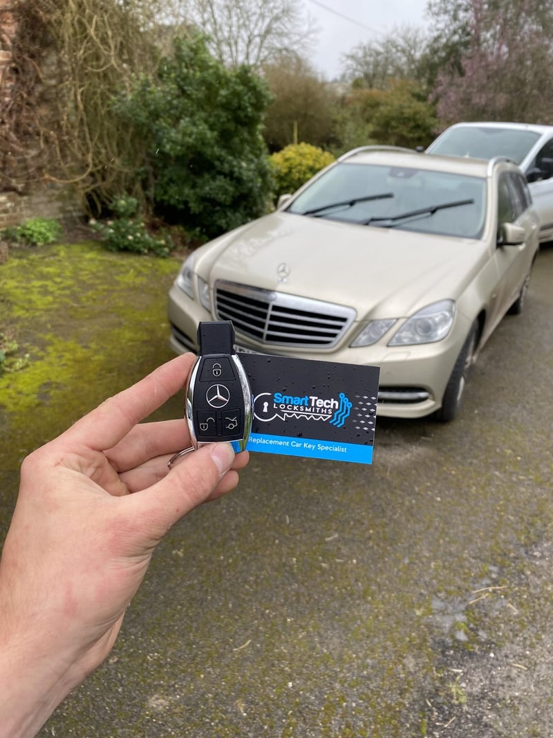 Mercedes-Benz E-Class spare key in Hampshire by SmartTech Auto Locksmiths, key and business card held in front of the vehicle
