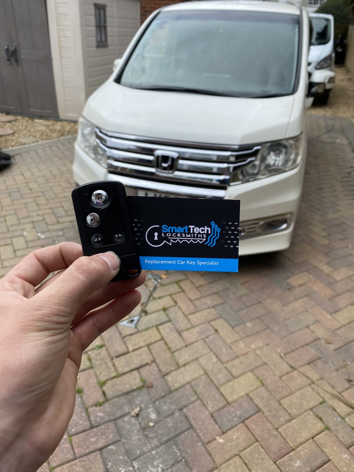 Honda Stepwgn replacement smart key in Hampshire by SmartTech Auto Locksmiths, key and business card held in front of the vehicle