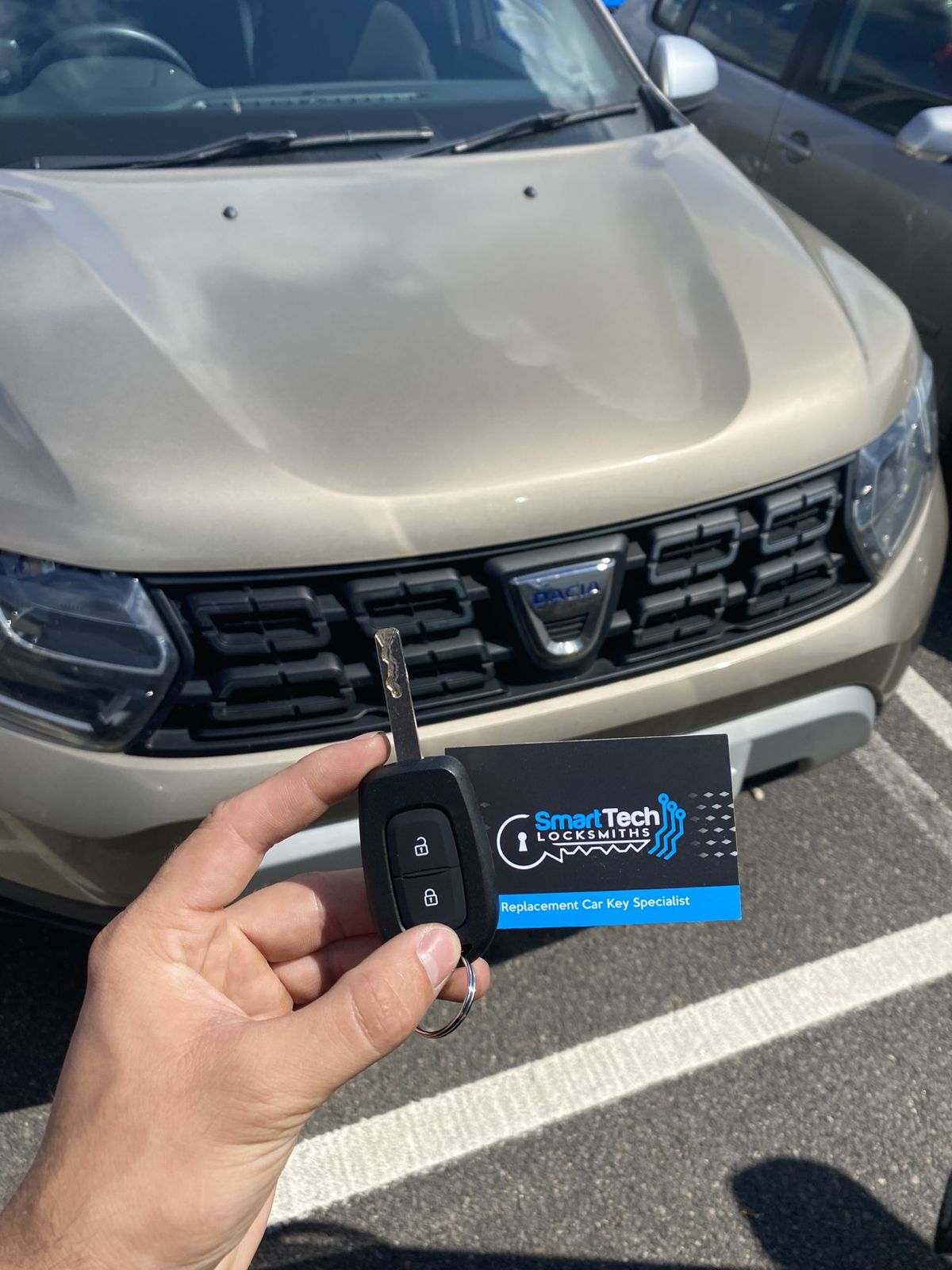 Dacia Duster replacement remote key in Lymington by SmartTech Auto Locksmiths, key and business card held in front of the vehicle