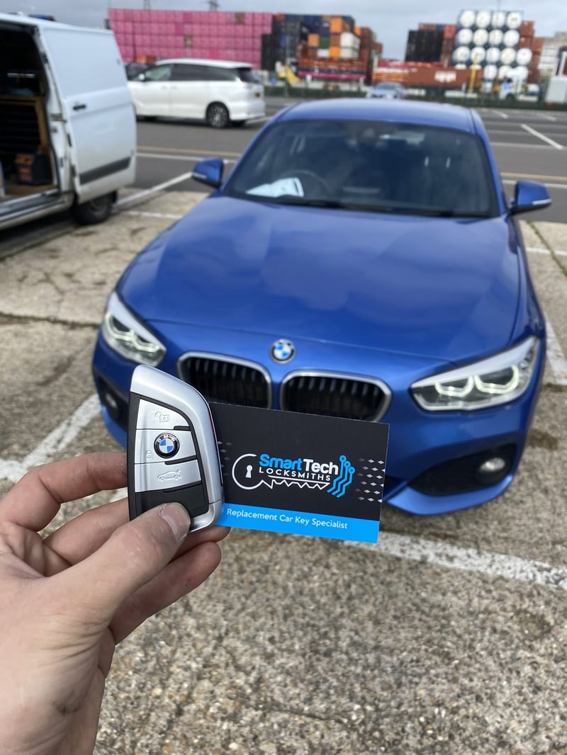 BMW 1 Series smart key programmed in Hampshire by SmartTech Auto Locksmiths, key and business card held in front of the vehicle
