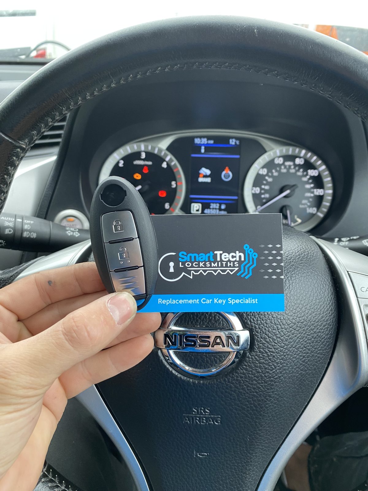 Nissan Navara smart key programmed in Hampshire by SmartTech Auto Locksmiths, key and business card held in front of the vehicle