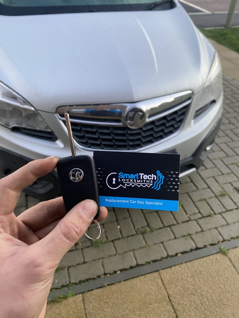 Vauxhall Mokka flip key cut and coded in Locks Heath & Warsash by SmartTech Auto Locksmiths, key and business card held in front of the vehicle