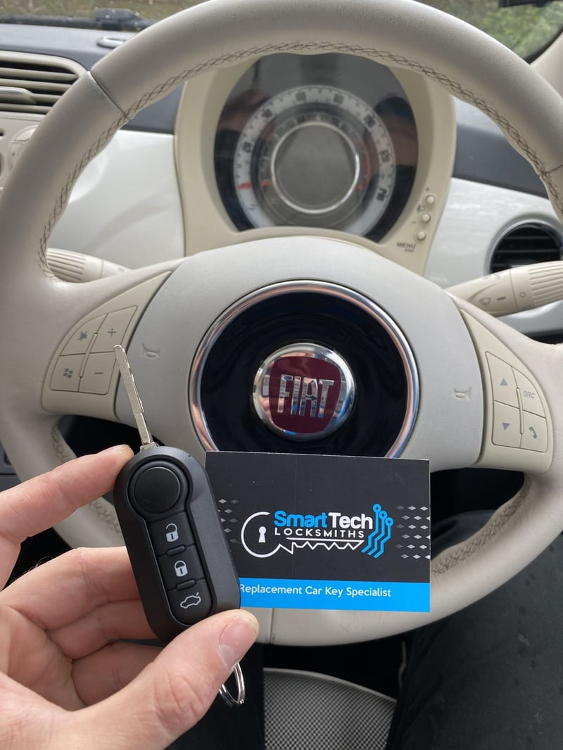 Fiat 500 flip key cut and coded in Hampshire by SmartTech Auto Locksmiths, key and business card held in front of the vehicle