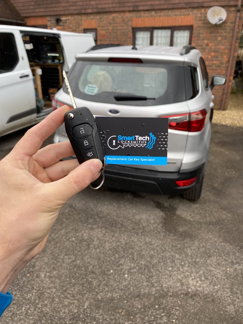 Ford EcoSport flip key cut and coded in Hampshire by SmartTech Auto Locksmiths, key and business card held in front of the vehicle