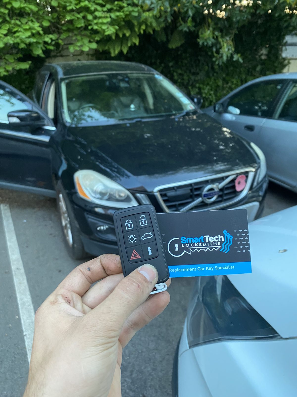 Volvo XC60 remote key programmed in Hampshire by SmartTech Auto Locksmiths, key and business card held in front of the vehicle