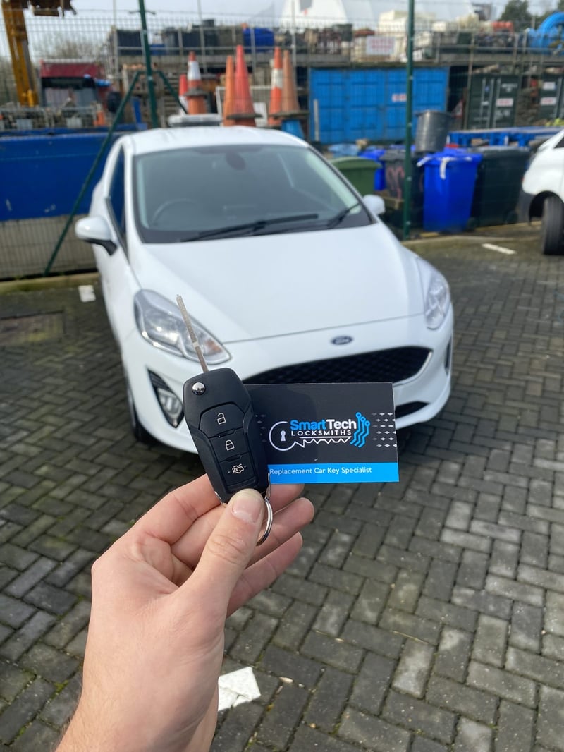 Ford Fiesta flip key cut and coded in Hampshire by SmartTech Auto Locksmiths, key and business card held in front of the vehicle