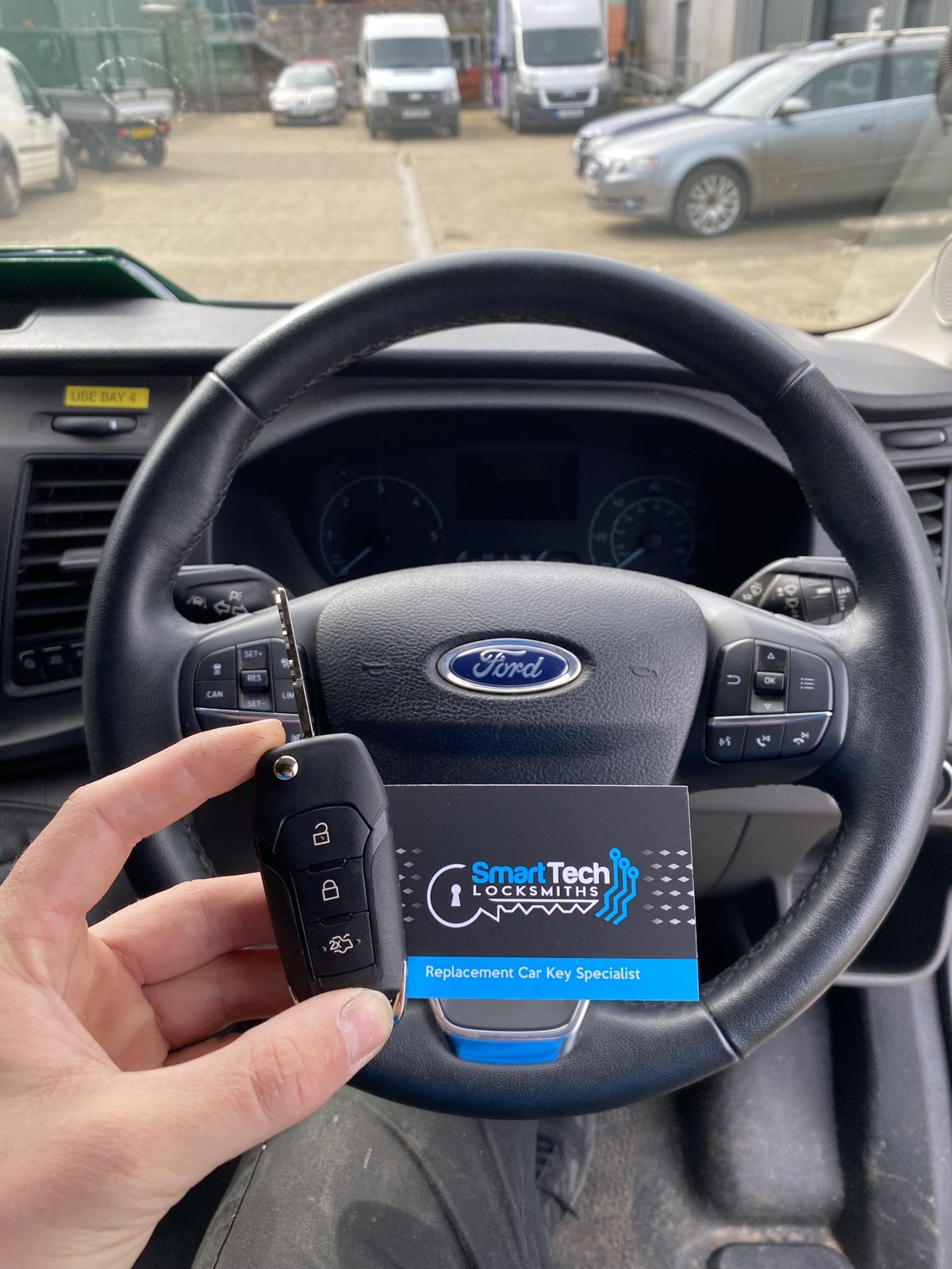 Ford Transit Custom van flip key programmed in Hampshire by SmartTech Auto Locksmiths, key and business card held in front of the vehicle