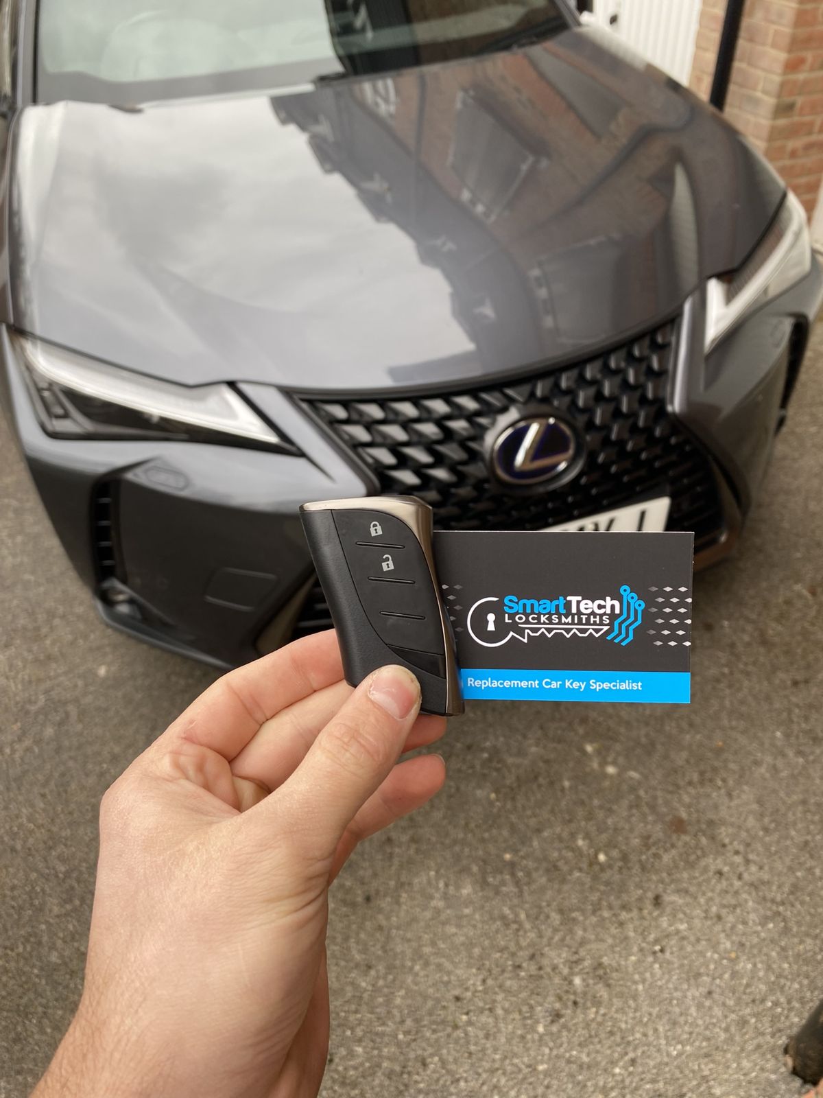 Lexus UX smart key programmed in Hythe & Dibden Purlieu by SmartTech Auto Locksmiths, key and business card held in front of the vehicle