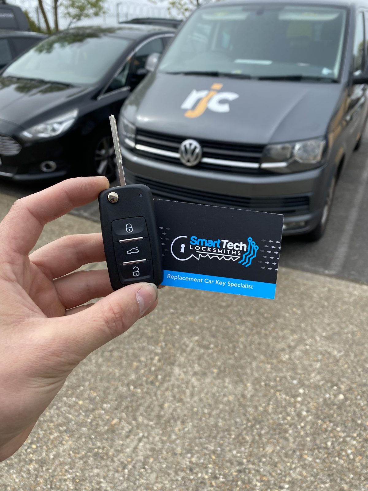 Volkswagen Transporter van flip key in Hampshire by SmartTech Auto Locksmiths, key and business card held in front of the vehicle