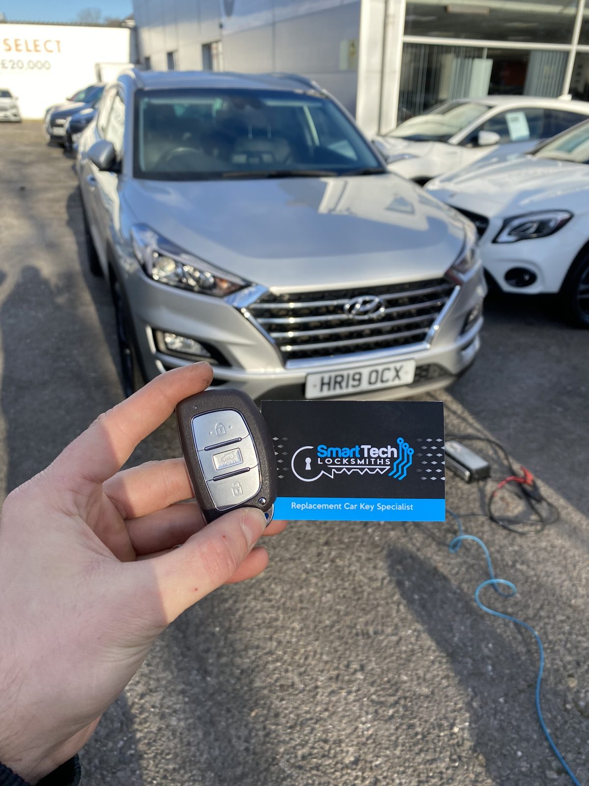 Hyundai Tucson spare smart key in Hedge End by SmartTech Auto Locksmiths, key and business card held in front of the vehicle