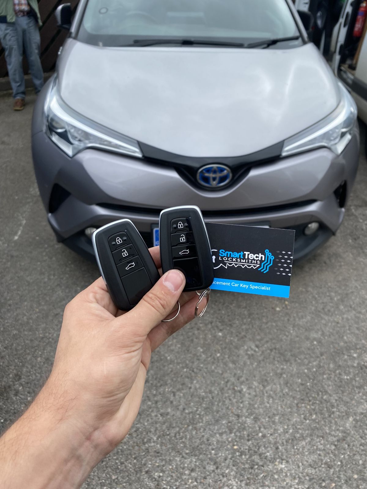 Toyota C-HR spare smart key in Netley & Hamble by SmartTech Auto Locksmiths, key and business card held in front of the vehicle