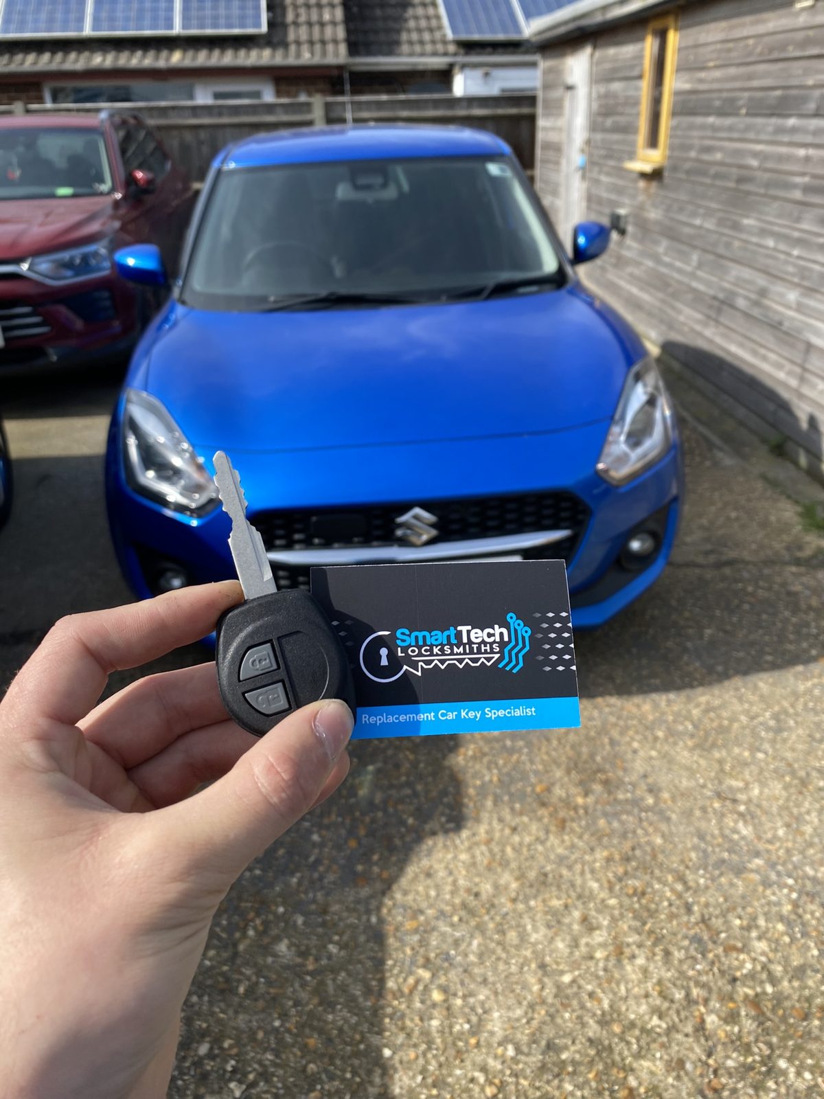 Suzuki Swift replacement key in Hampshire by SmartTech Auto Locksmiths, key and business card held in front of the vehicle