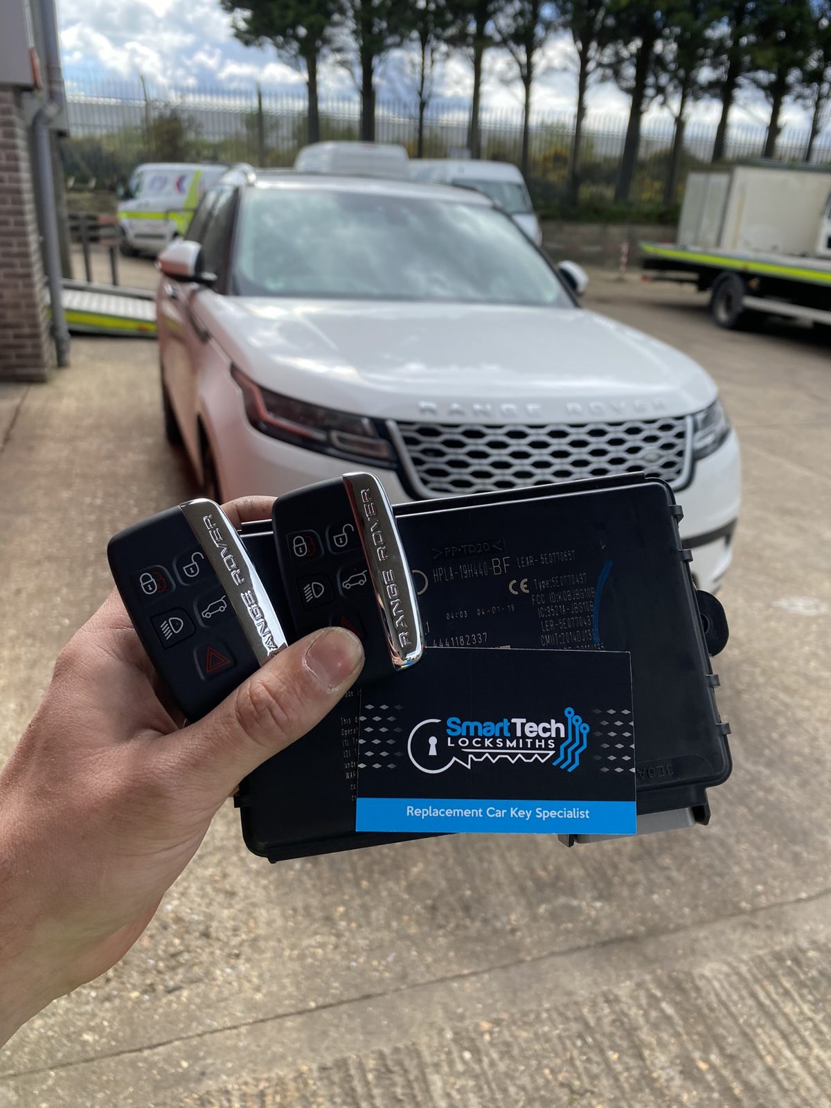 Range Rover Velar smart keys and module coded in Hampshire by SmartTech Auto Locksmiths, key and business card held in front of the vehicle