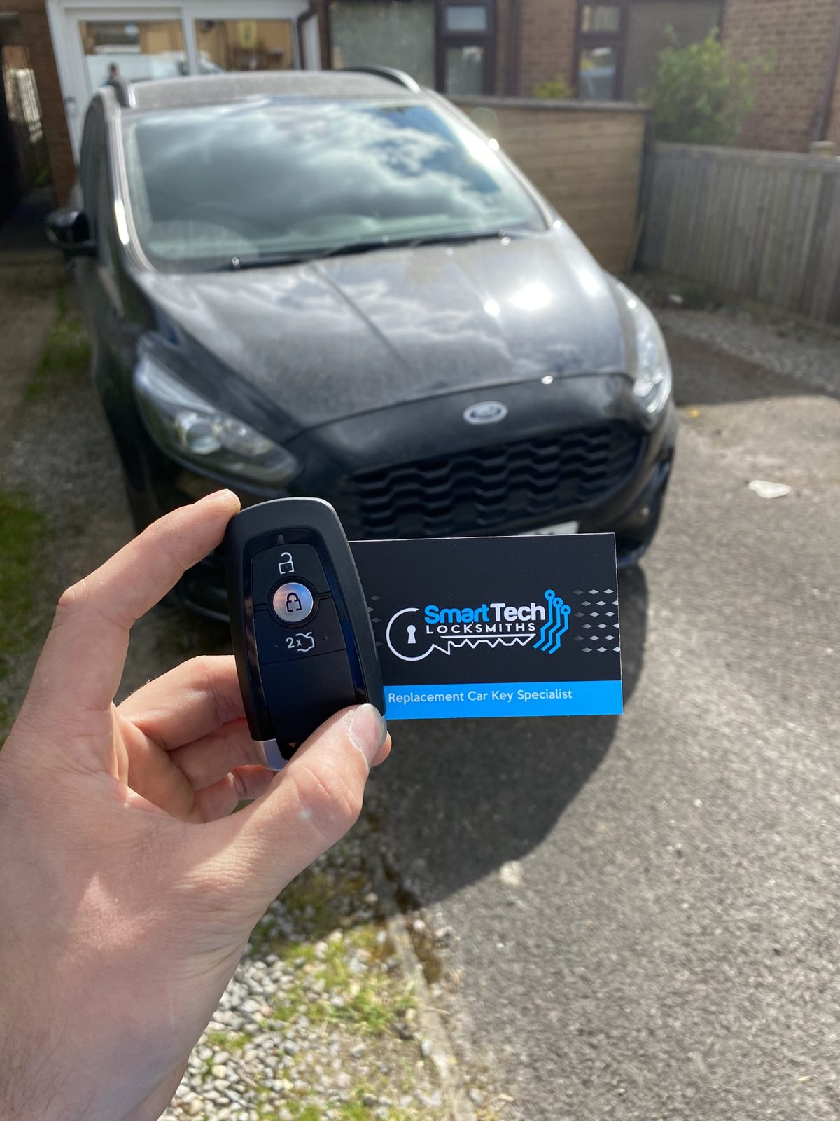 Ford S-Max smart key programmed in Hampshire by SmartTech Auto Locksmiths, key and business card held in front of the vehicle