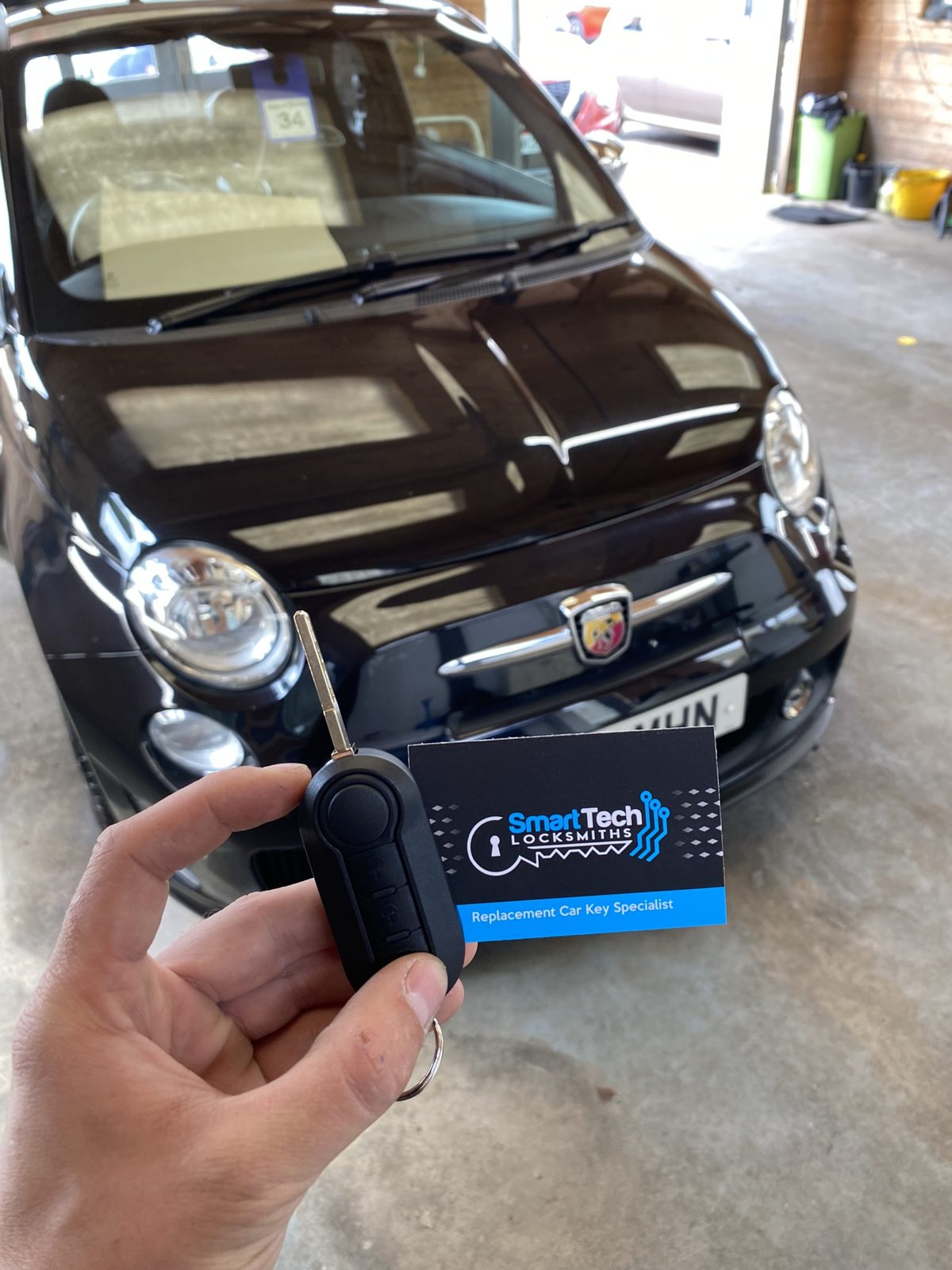 Abarth 500 flip key cut and coded in Hampshire by SmartTech Auto Locksmiths, key and business card held in front of the vehicle