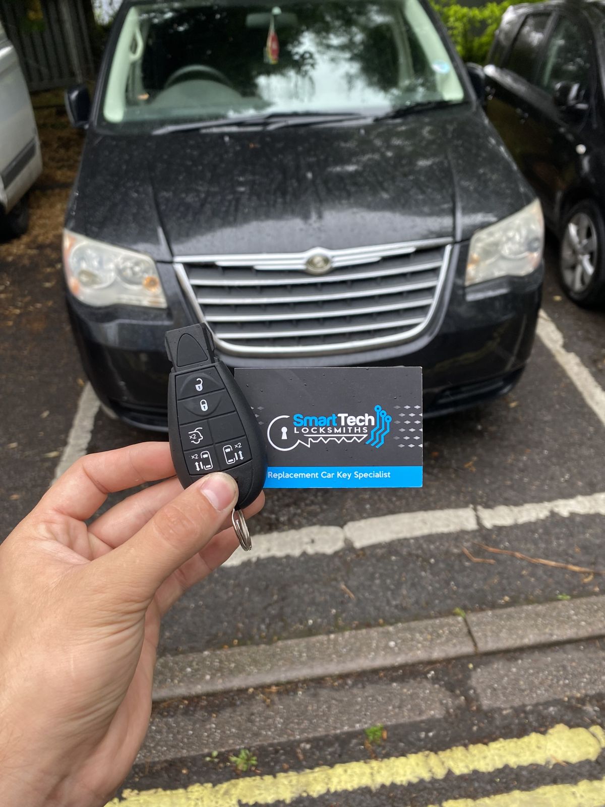 Chrysler Grand Voyager replacement remote key in Bitterne by SmartTech Auto Locksmiths, key and business card held in front of the vehicle