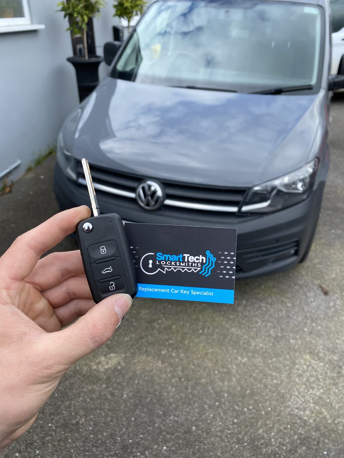 Volkswagen Touran flip key cut and coded in Hampshire by SmartTech Auto Locksmiths, key and business card held in front of the vehicle