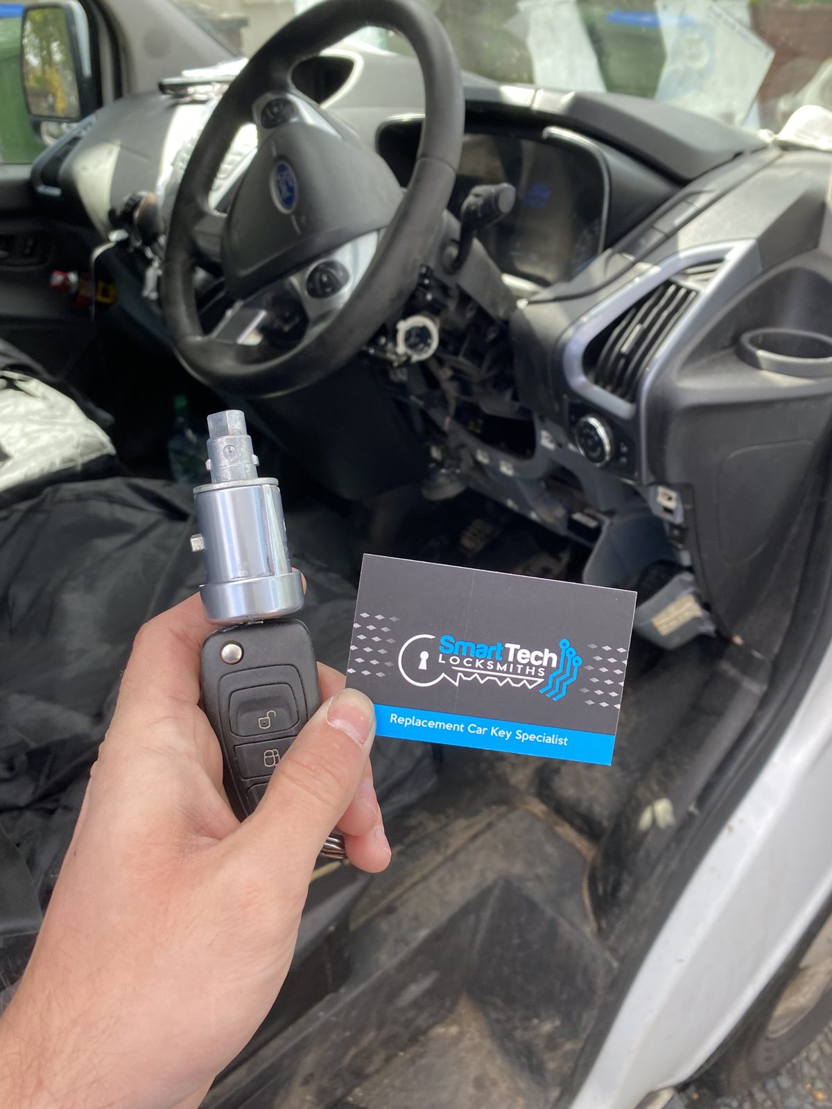 Ford Transit ignition lock replaced in Hampshire by SmartTech Auto Locksmiths, key and business card held in front of the vehicle