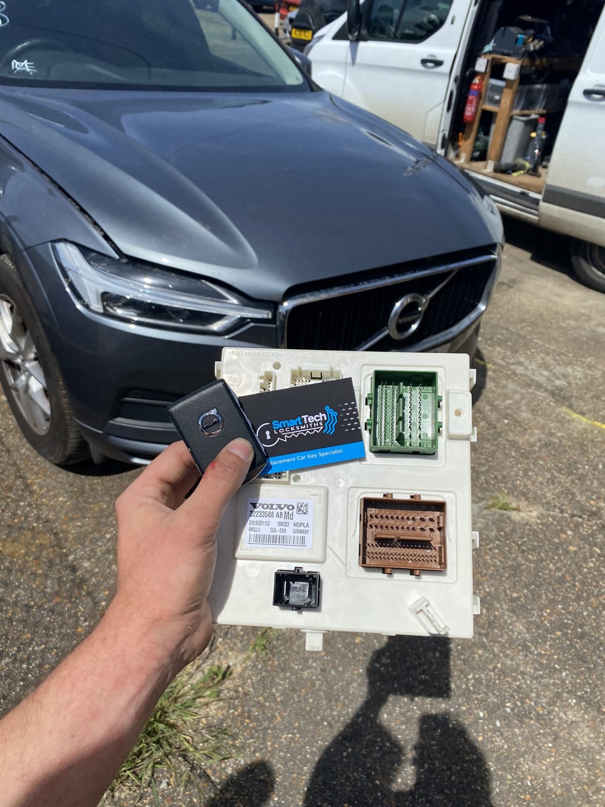 Volvo XC60 module and key coded in Hampshire by SmartTech Auto Locksmiths, key and business card held in front of the vehicle